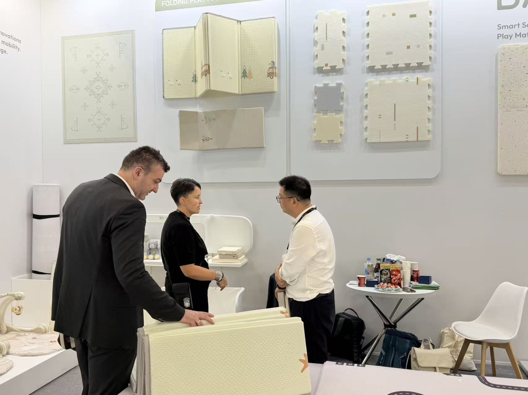 Michael Chen discussing new BABYGO play mats with international visitors at Kind + Jugend Cologne 2026